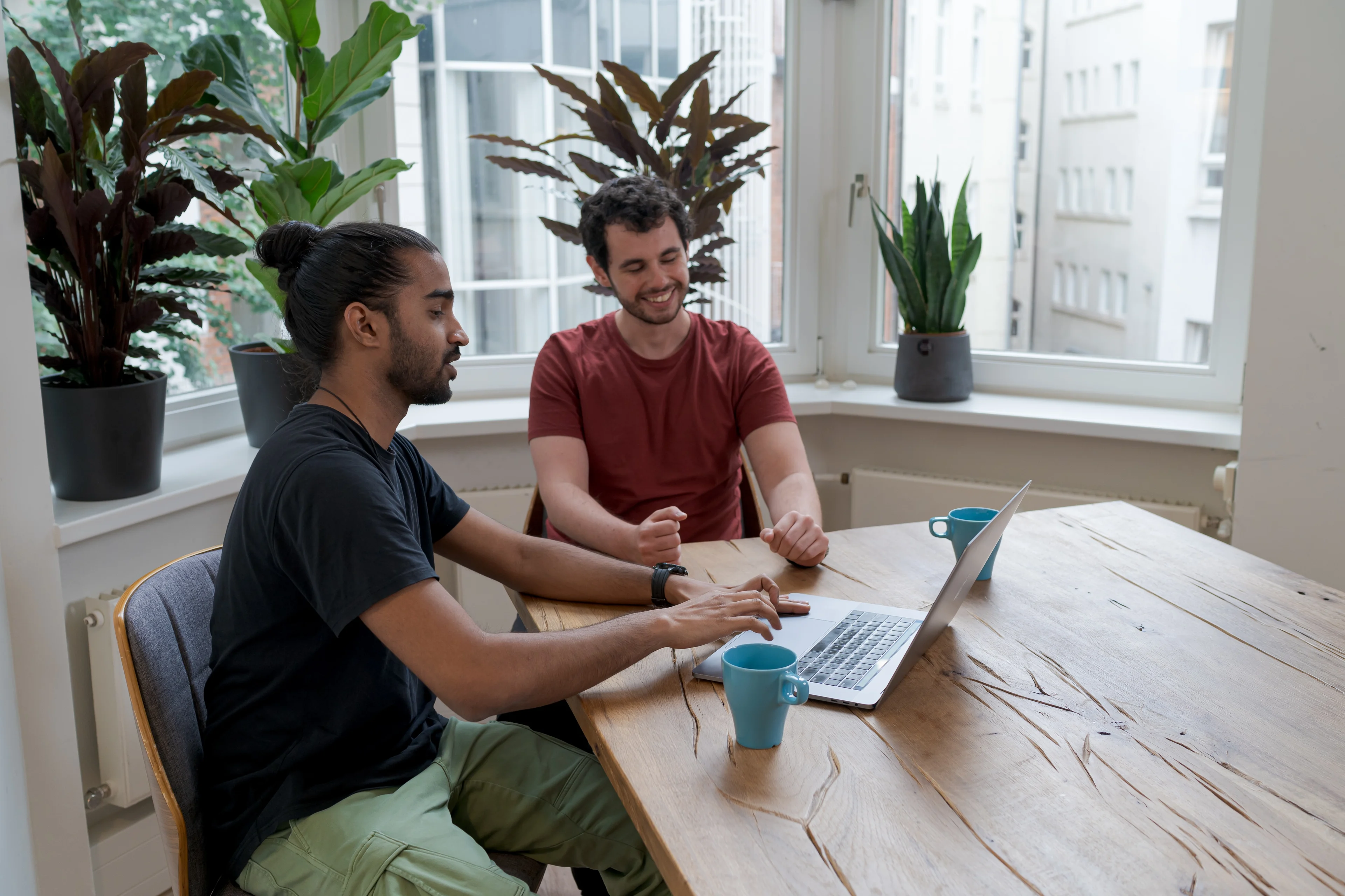 Two men sitting by a desk working on a laptop